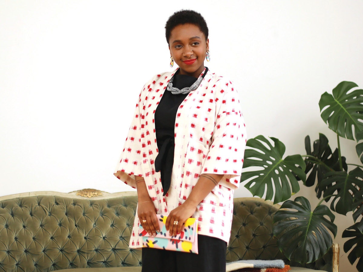 Model wearing a black linen jumpsuit, printed kimono, and colorful accessories