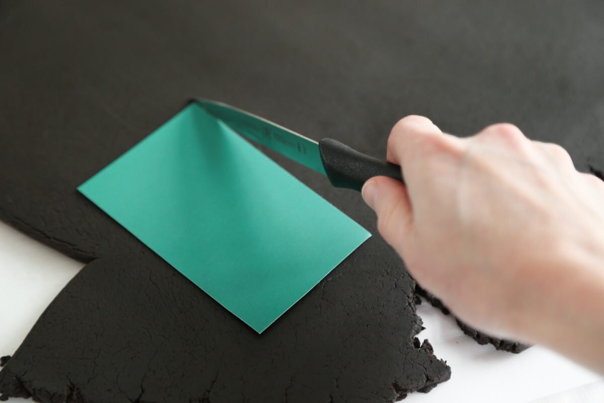 Heather cuts cassette-shaped cookies out of the dough using the cookie template.