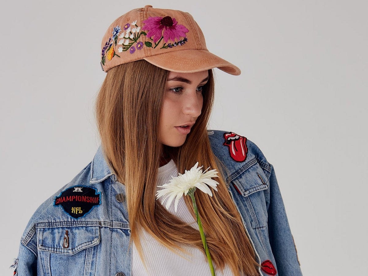 A girl modeling an embroidered baseball cap and denim jacket