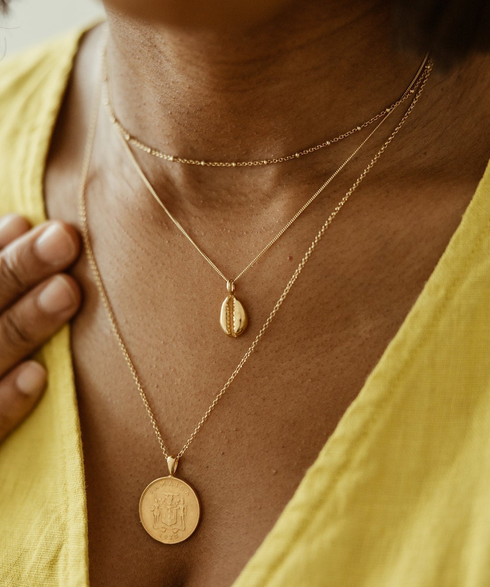 Gold Jamaican coin necklace and coffee bean necklace both from Omi Woods