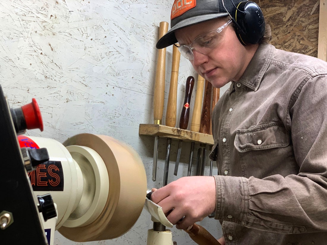 Martinus turns a piece of WIP wood on a lathe.