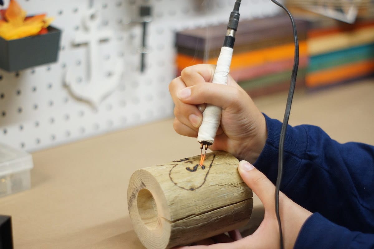 Sarah personalizes a custom wooden candle holder with initials