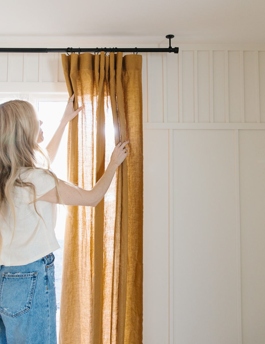 Sarah opens the amber-colored linen drapes while sunshine beams through them.