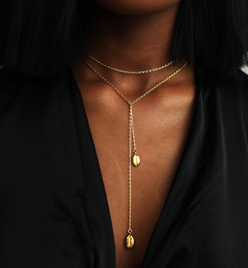 A woman models an infinity cowrie necklace from Omi Woods