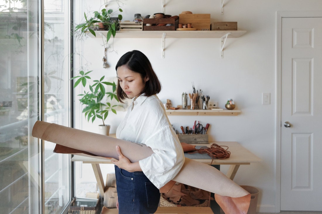 Quynh holding a large roll of uncut leather