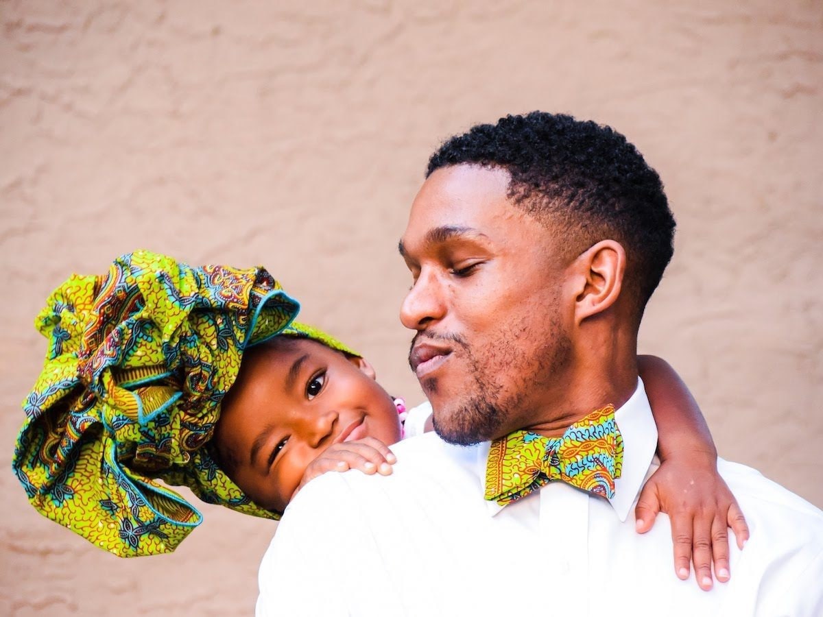 Father and daughter wearing matching African wax print bow tie and headwrap