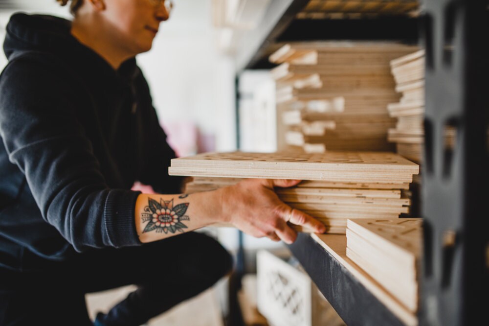 Hanna stacks pieces of unassembled wood crates on a shelf.