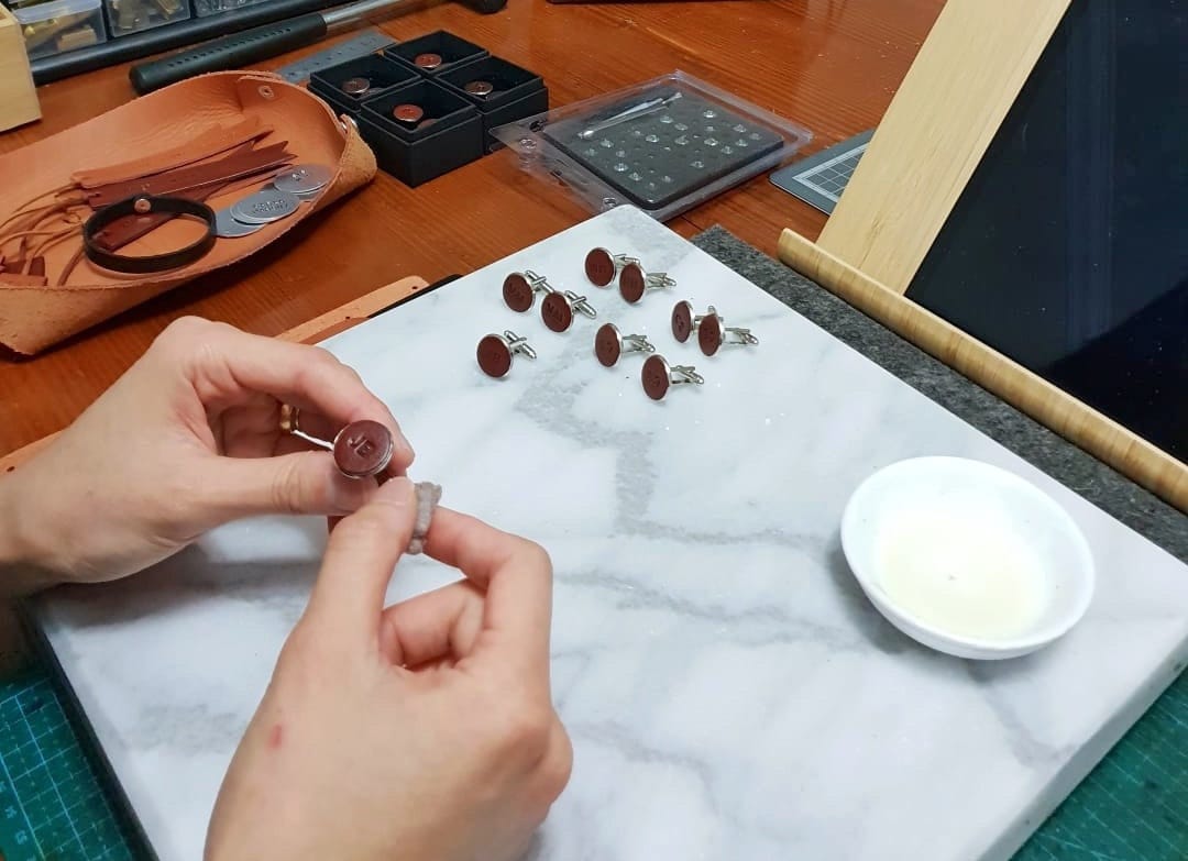 Pauline polishes a leather cufflink