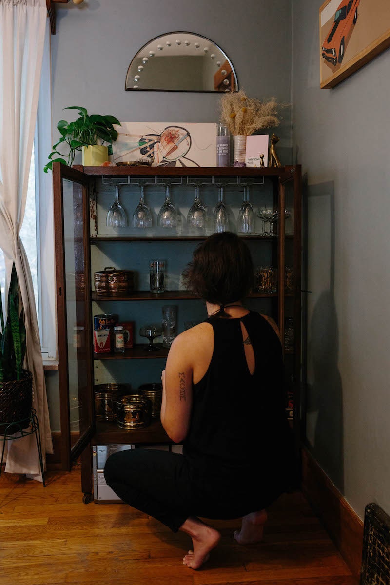 Brenda arranging glassware on a shelf in her home