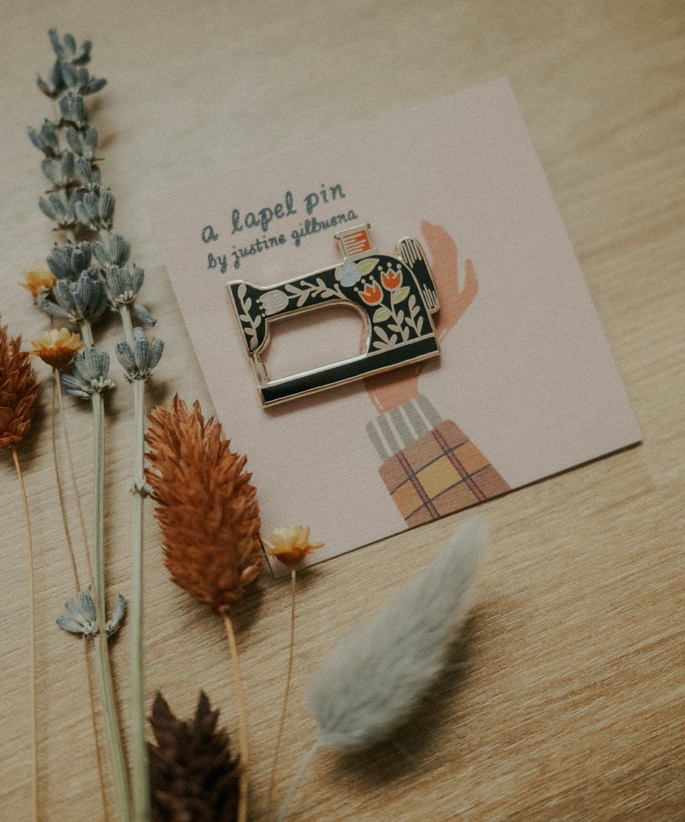 A sewing machine enamel pin from Justine Gilbuena