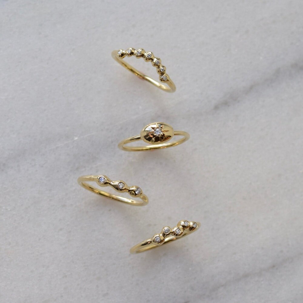 A curved diamond ring, diamond star ring, simple diamond band, and diamond constellation ring from Everli