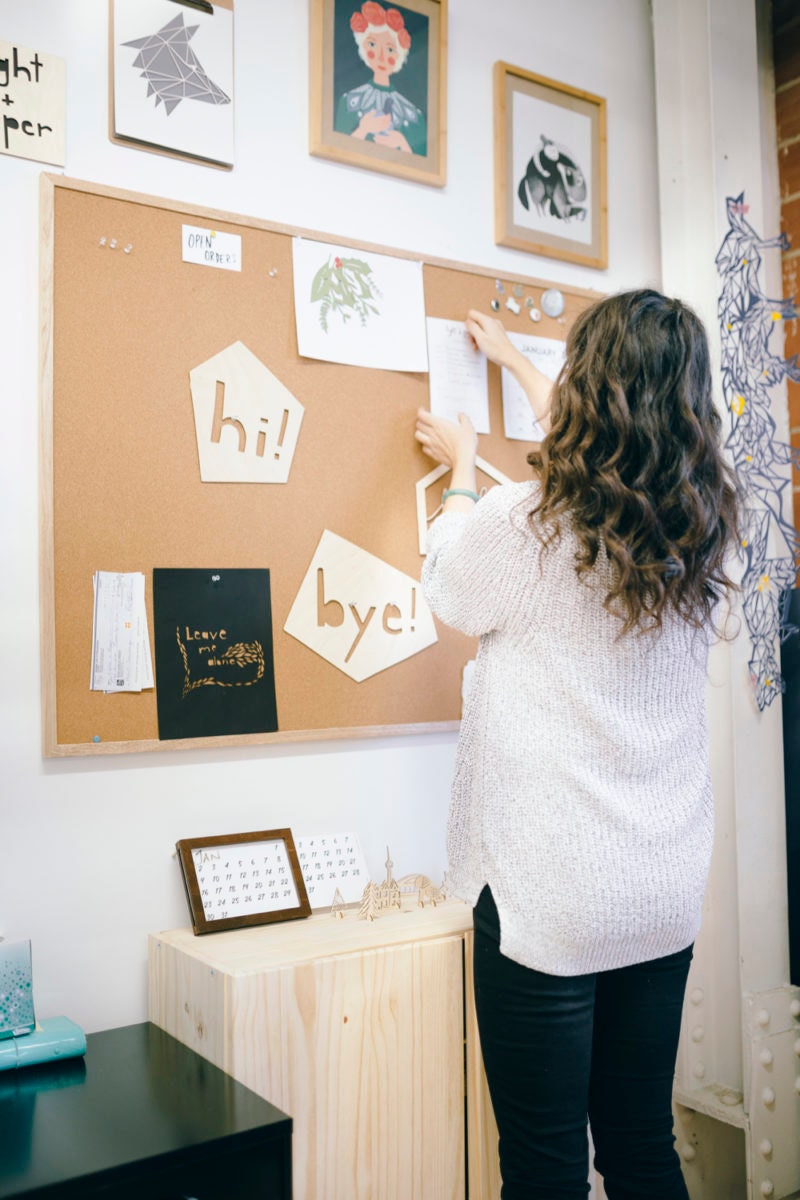 Ali hanging up notes on her bulletin board in her studio.