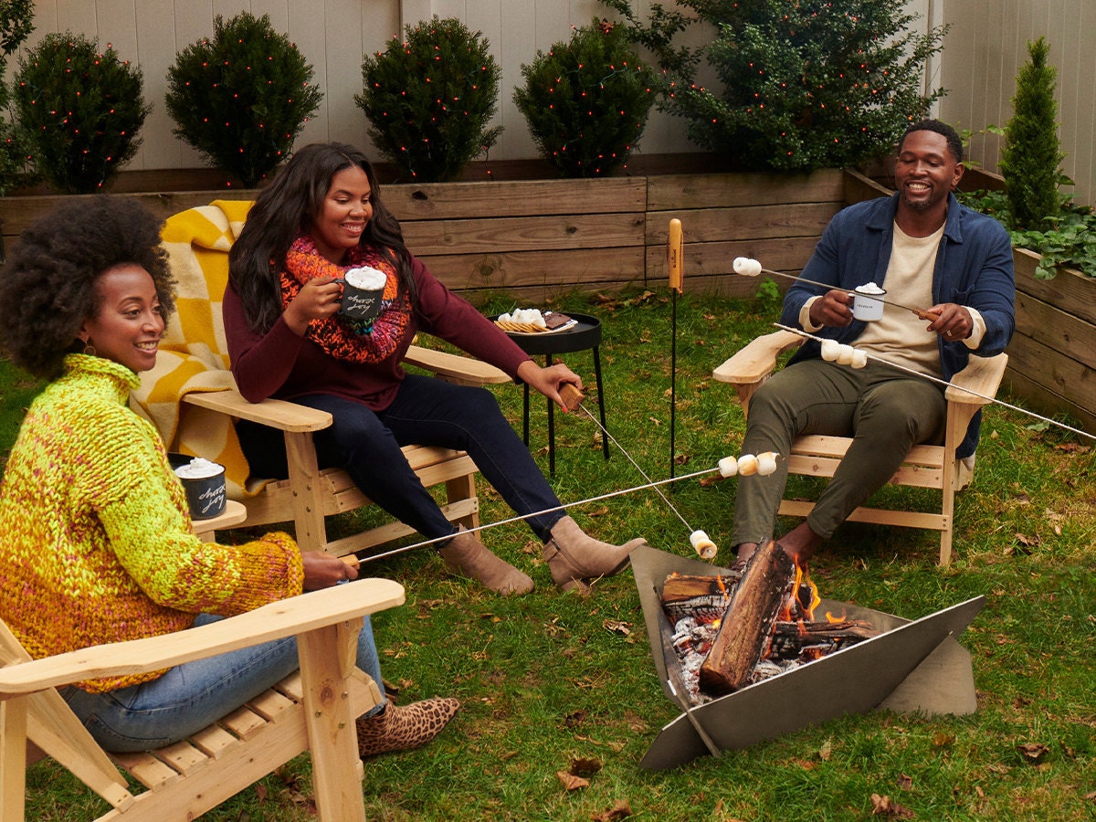 Three people sit around an outdoor firepit