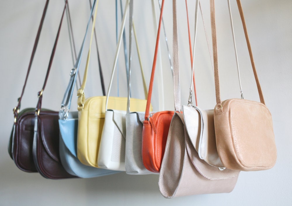 A rainbow-colored assortment of handbags from Alex Bender hanging from a rack