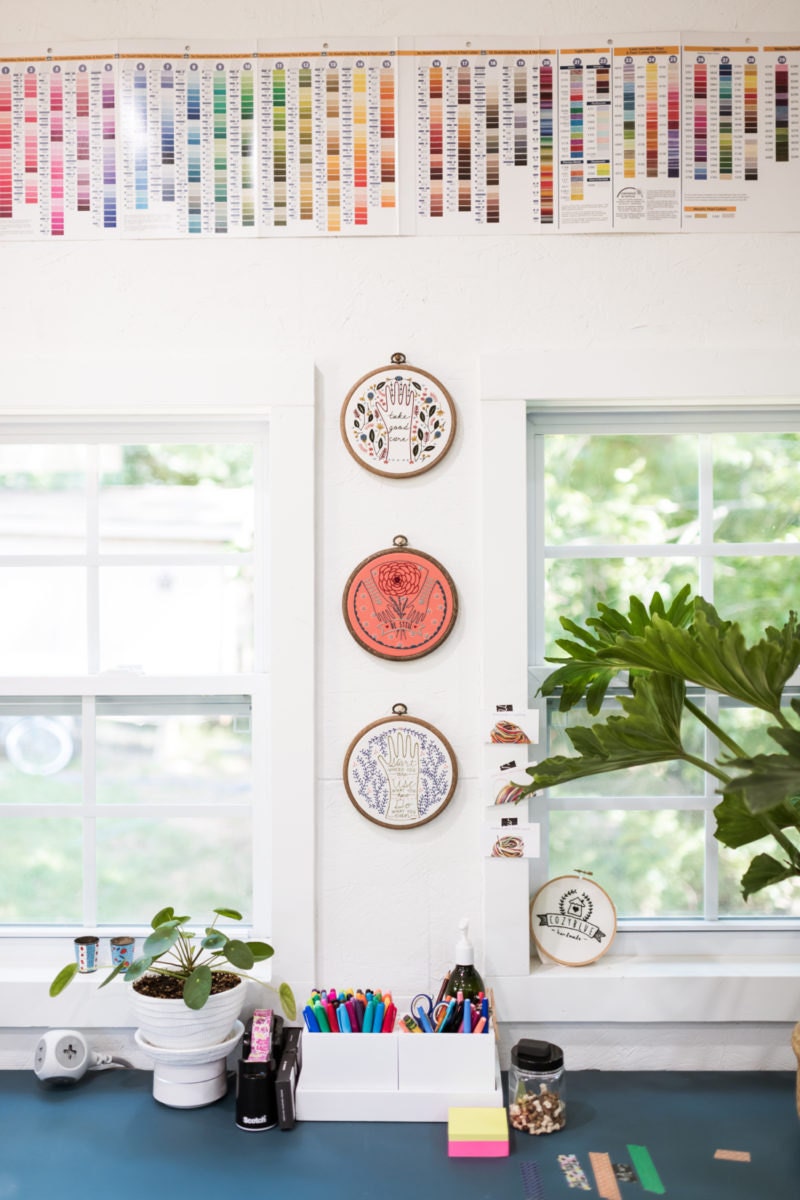 Finished embroidery hoops on display above Liz's desk