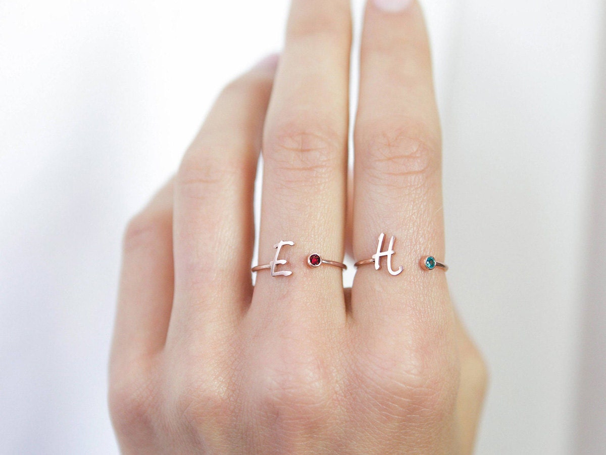 Two initial and birthstone rings on a model.