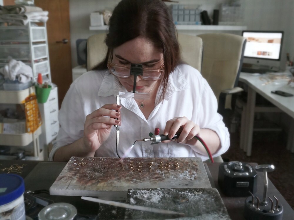 Aleisha uses a blowtorch to solder her squiggle earrings.