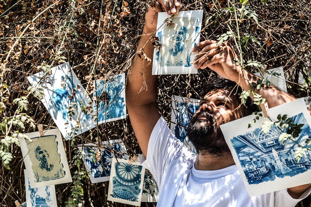 A person hanging up cyanotype prints in the sun
