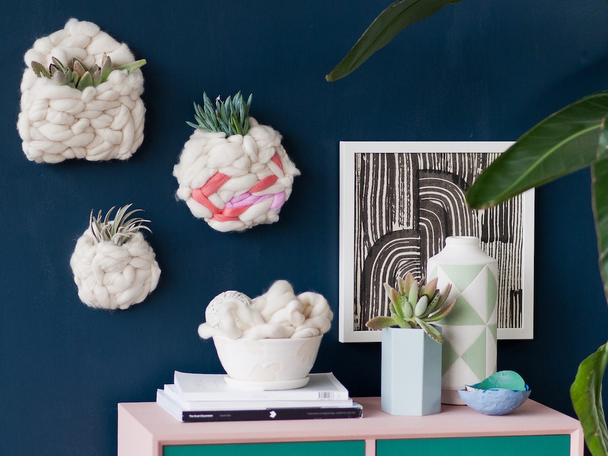 DIY woven wall pockets filled with plants, hanging above a desk