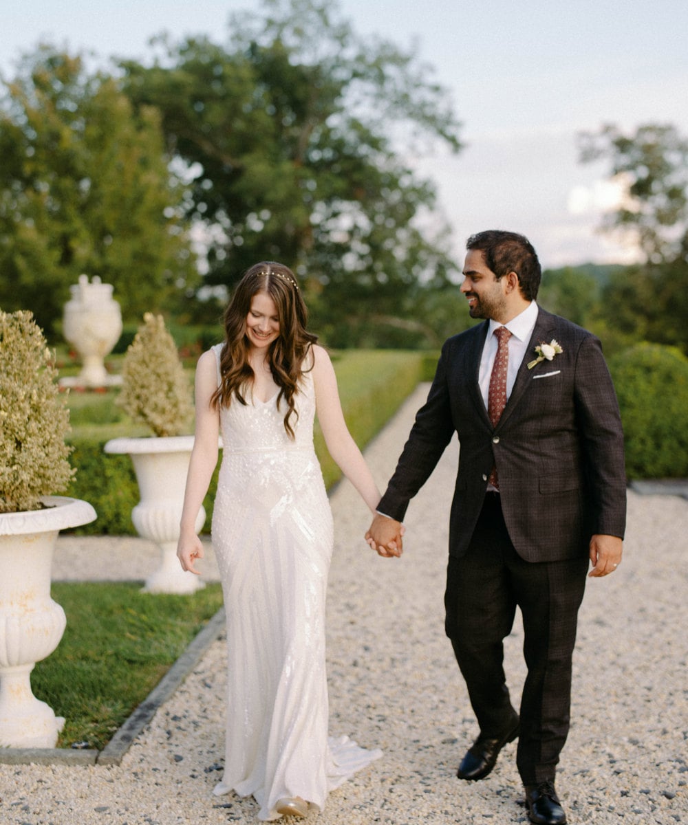 A portrait of Megan Oppenheimer and Imran Hoosain holding hands on their wedding day.