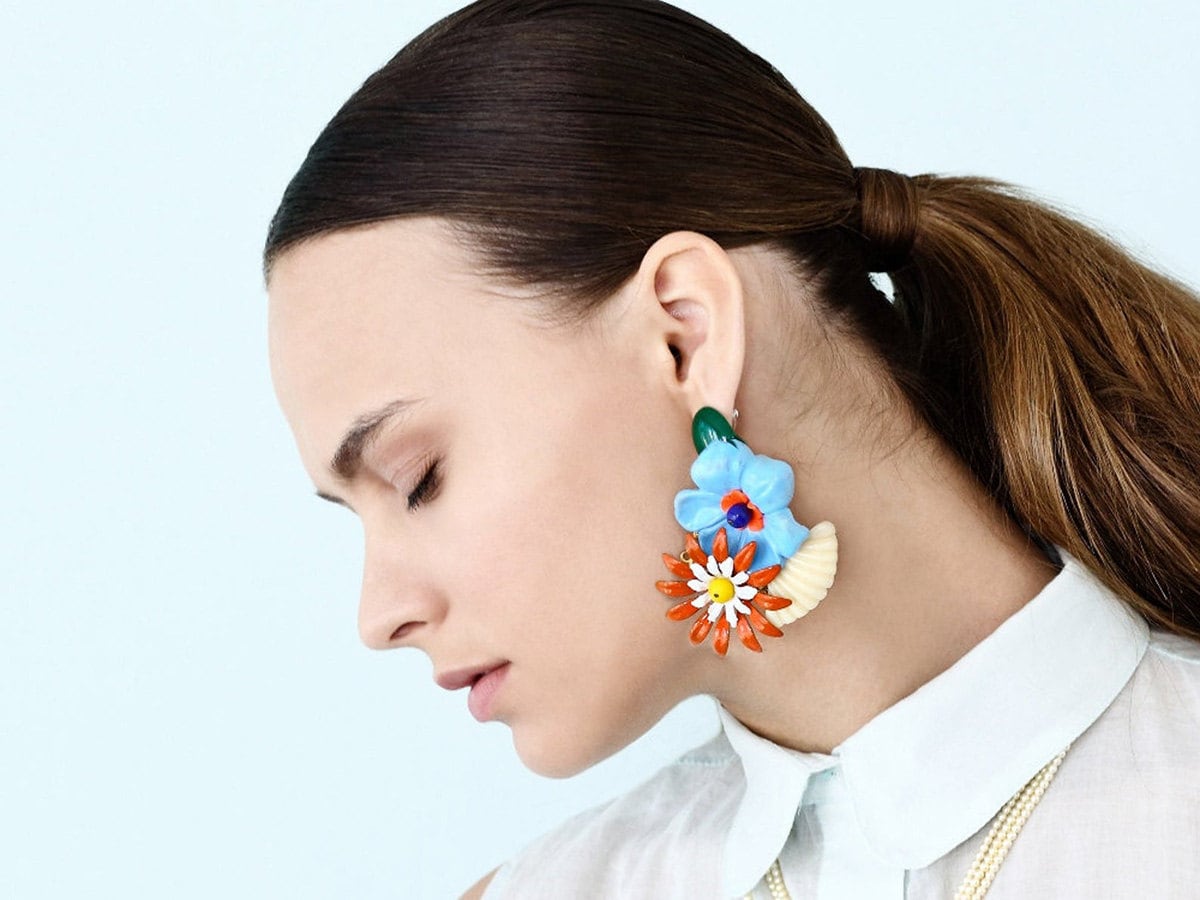 Enamel flower earrings on a model.