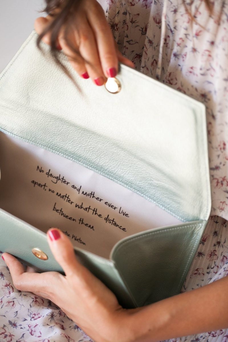 A woman holds open a personalized clutch from Fontém to see the note inside.