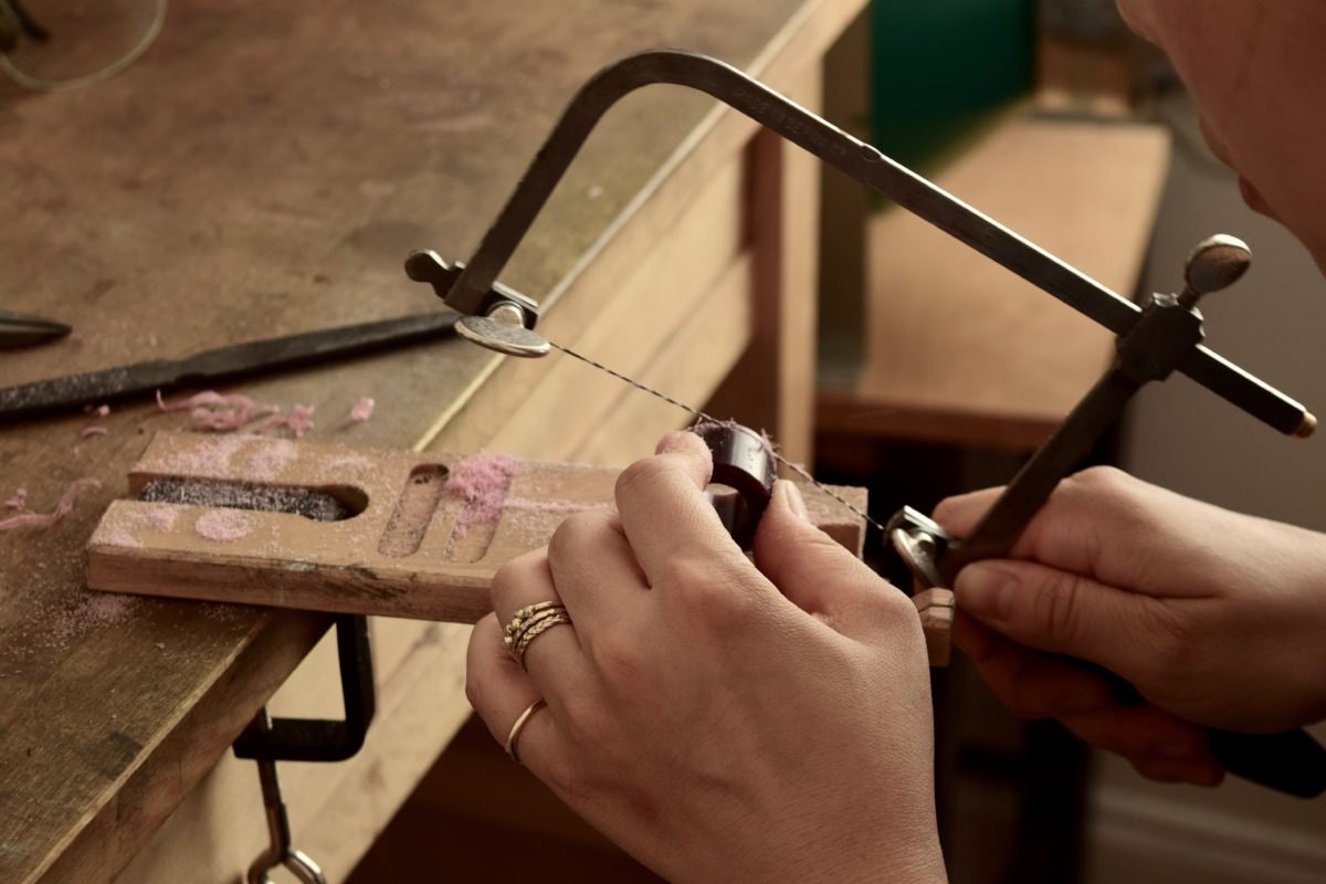 Shuang cutting metal at her workbench