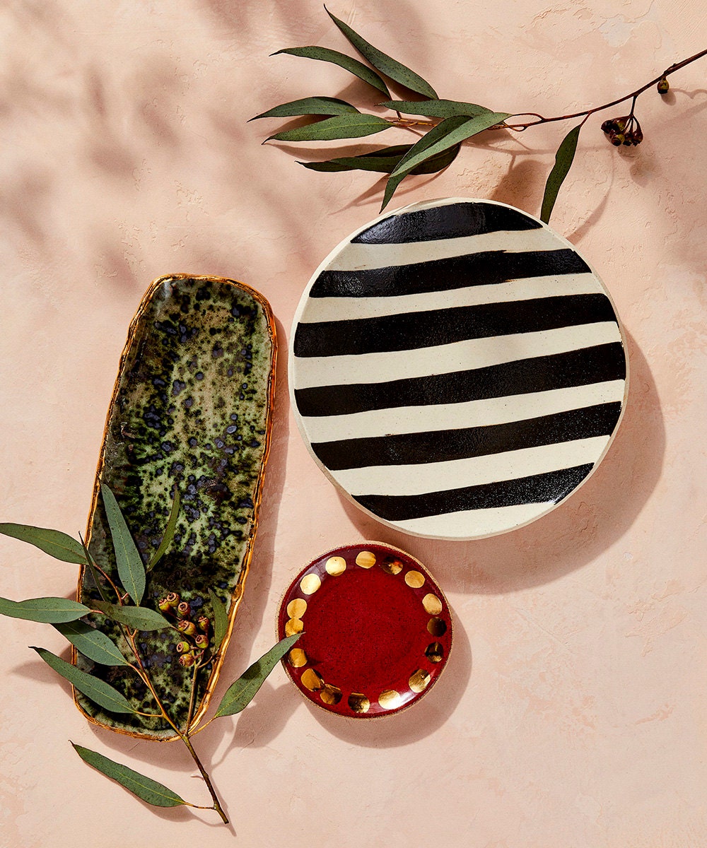 Decorative trays and jewelry dishes against a pink backdrop.