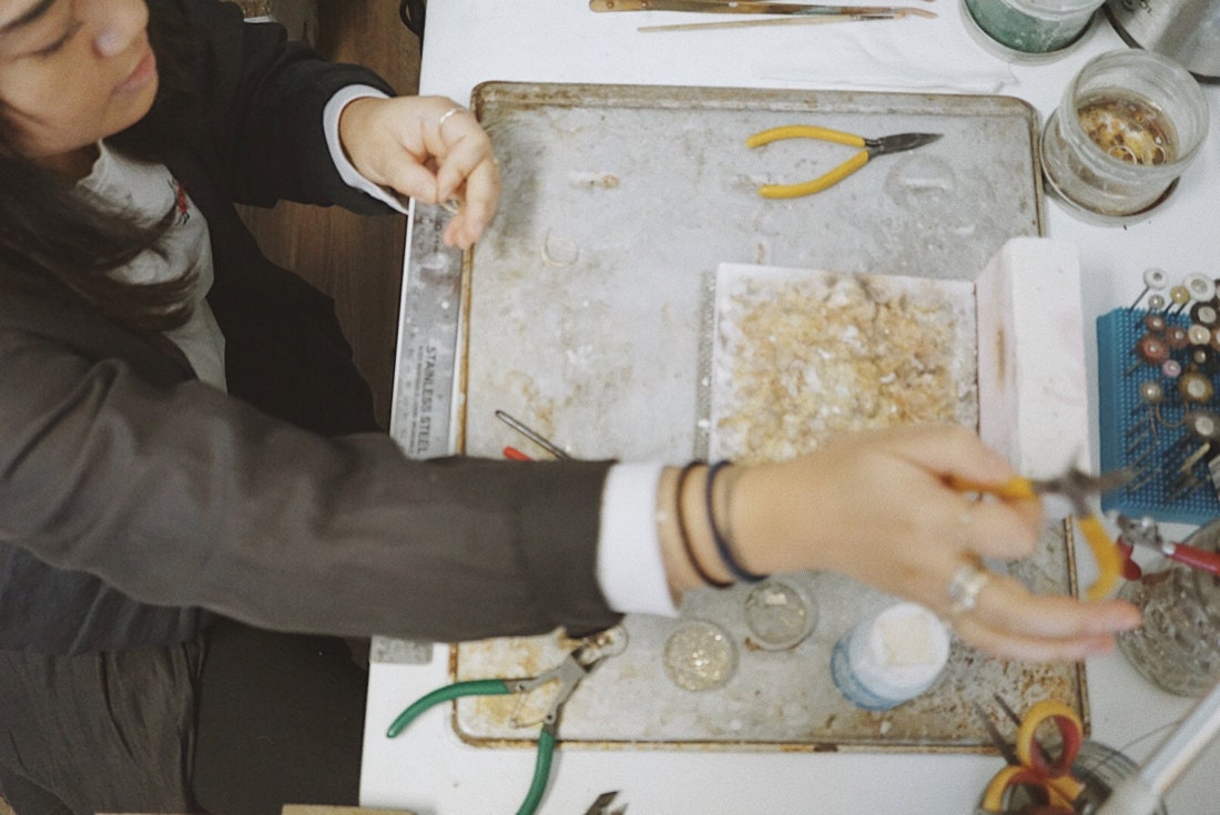 Katherine selects the proper pair of pliers to begin work on one of her gold jewelry pieces.