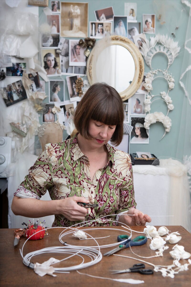 Rae at her workbench cutting wire that will be used to give structure to a floral halo crown.