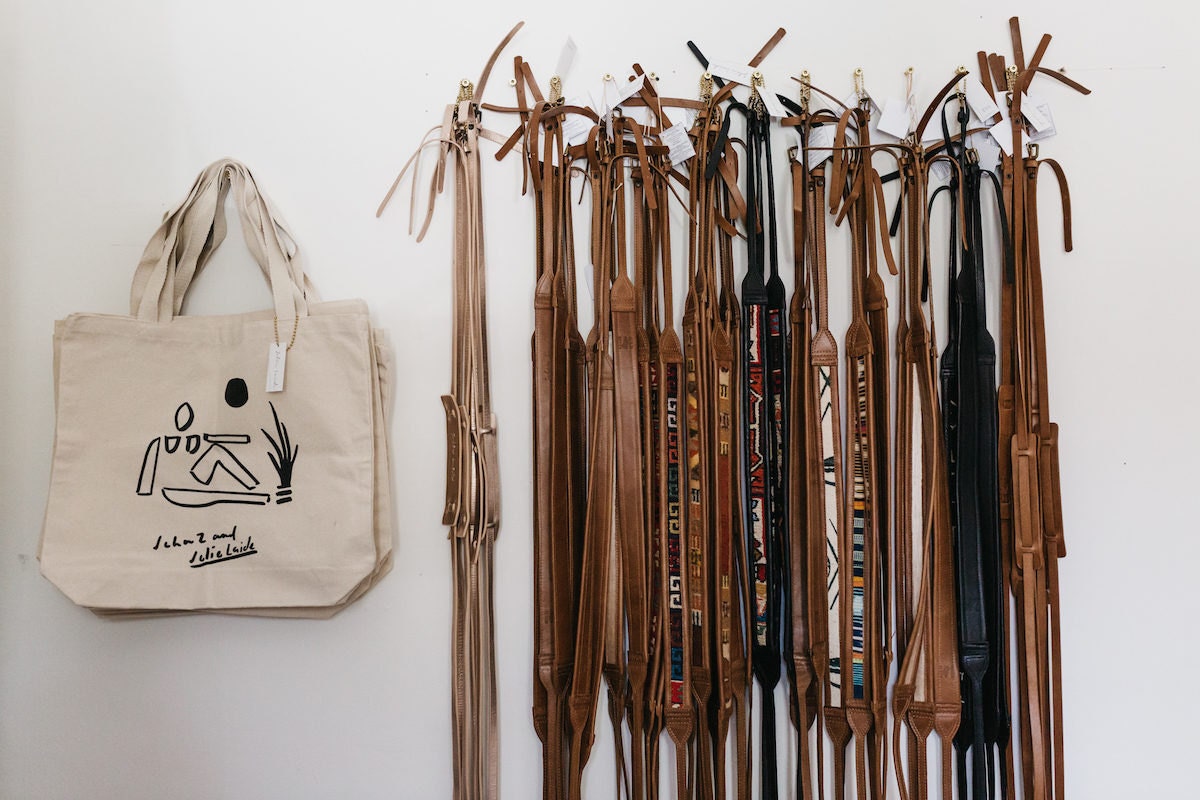 Leather camera straps and canvas tote bags hanging on a wall