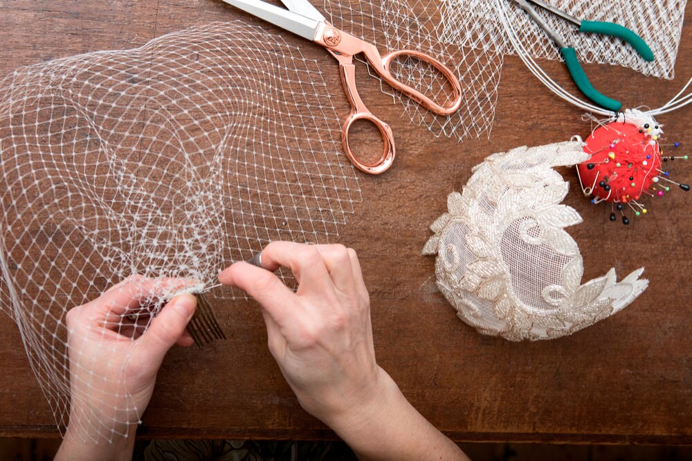 Rae sews a comb onto a piece of French netting to create a birdcage veil.