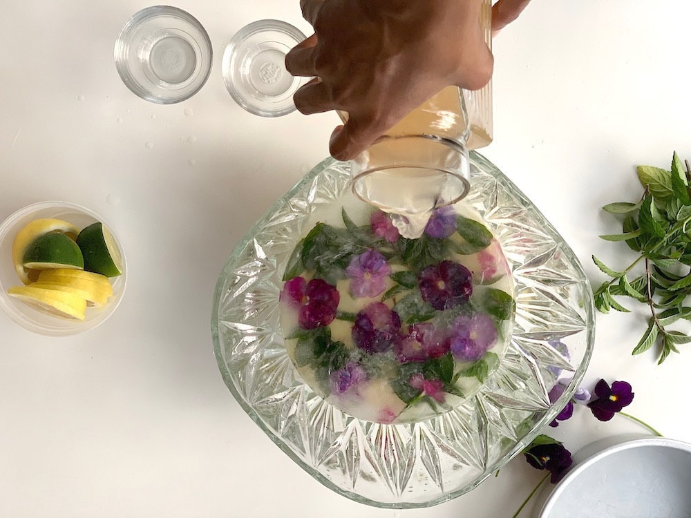 Aravis pours her punch mixture over the finished ice block, which is nestled in a crystal punch bowl.