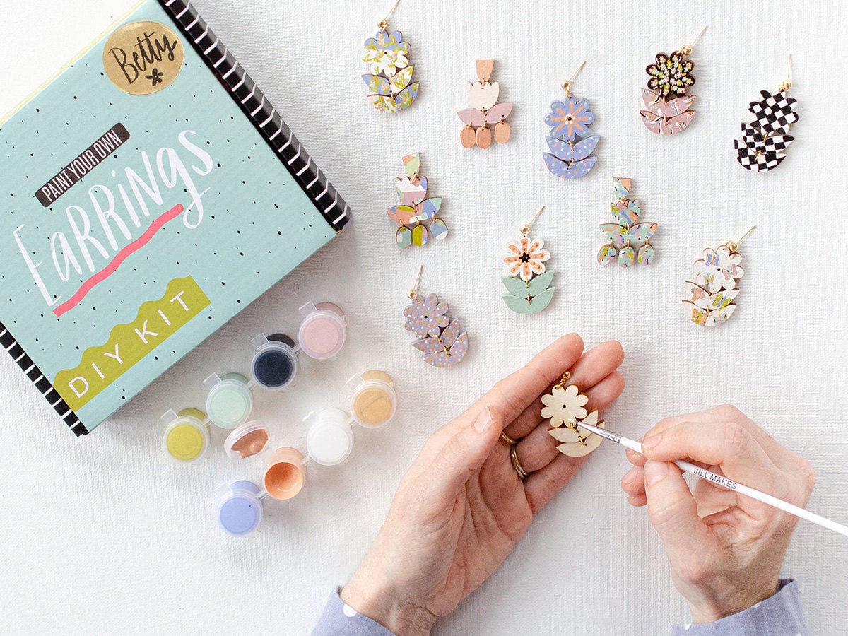 A model paints statement earrings using a DIY kit.