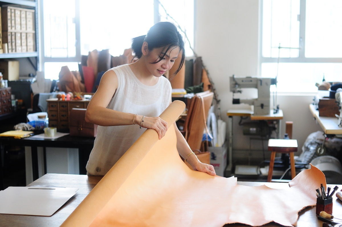 Joe unfurling a roll of leather in her studio