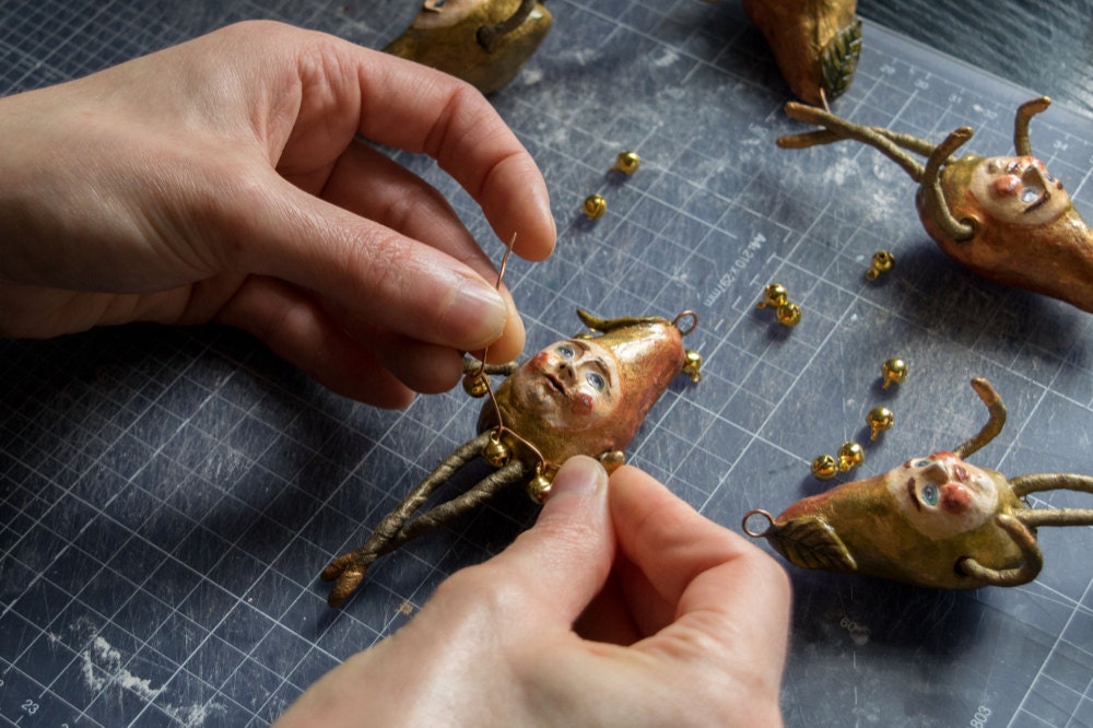 Kayleigh creates a tiny bell collar for her gold pear ornament