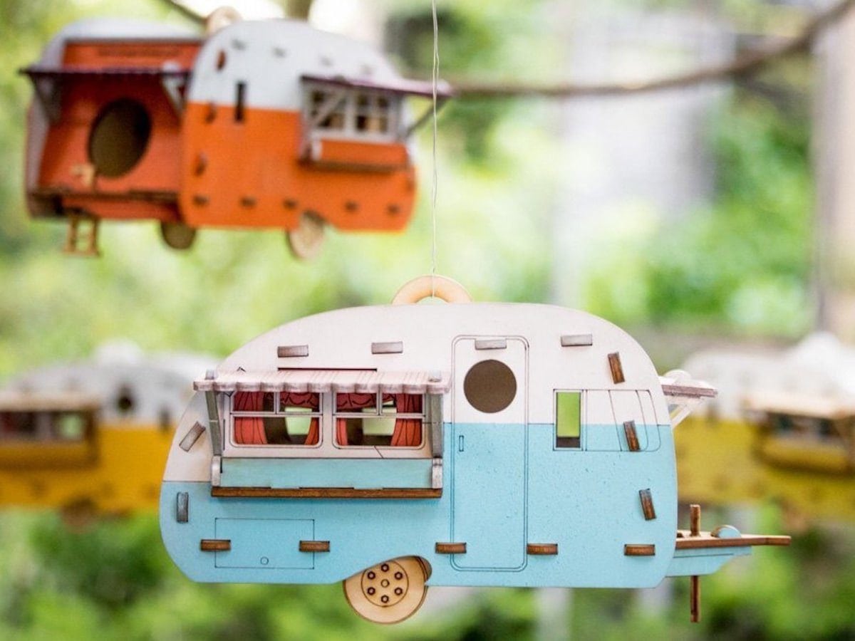 Two camper-style birdhouses hanging from a tree.