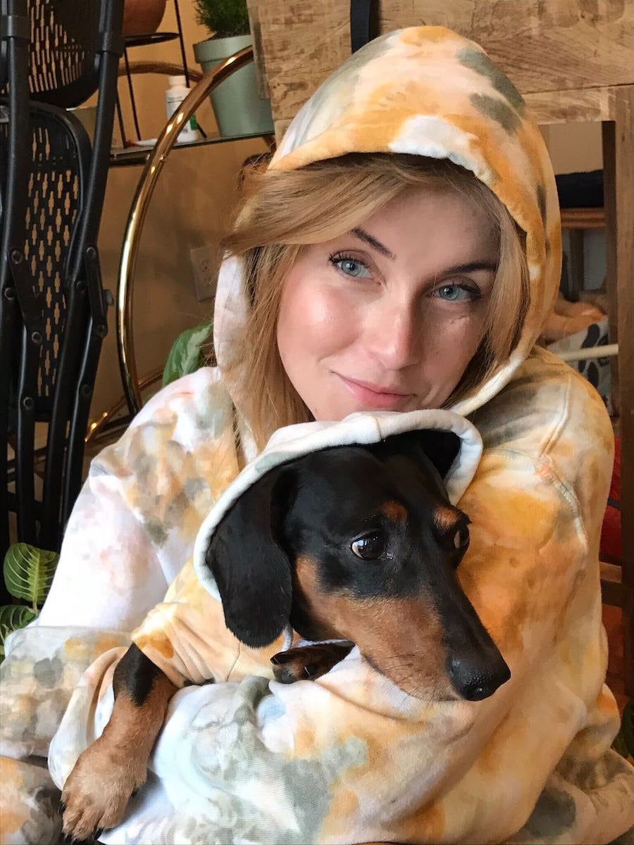 A woman and her dog model their matching tie-dyed sweatshirts.