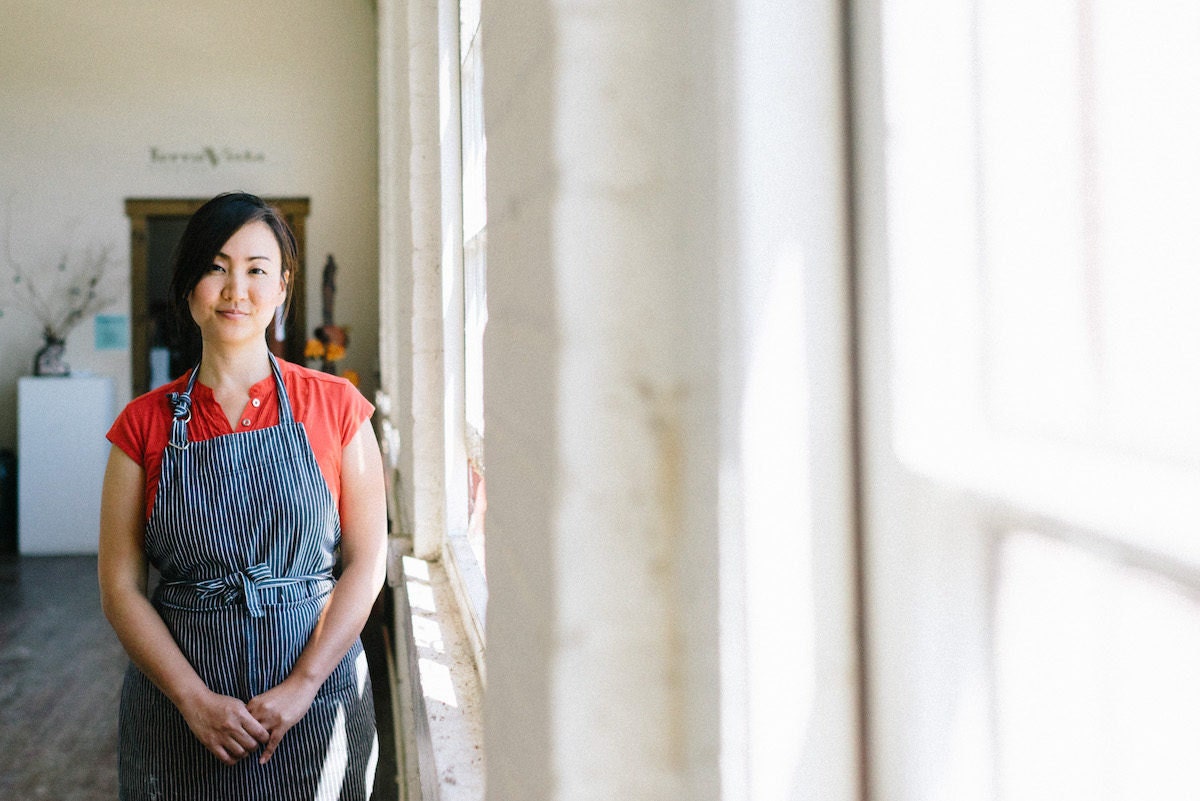 Yumiko stands next to the windows in her studio