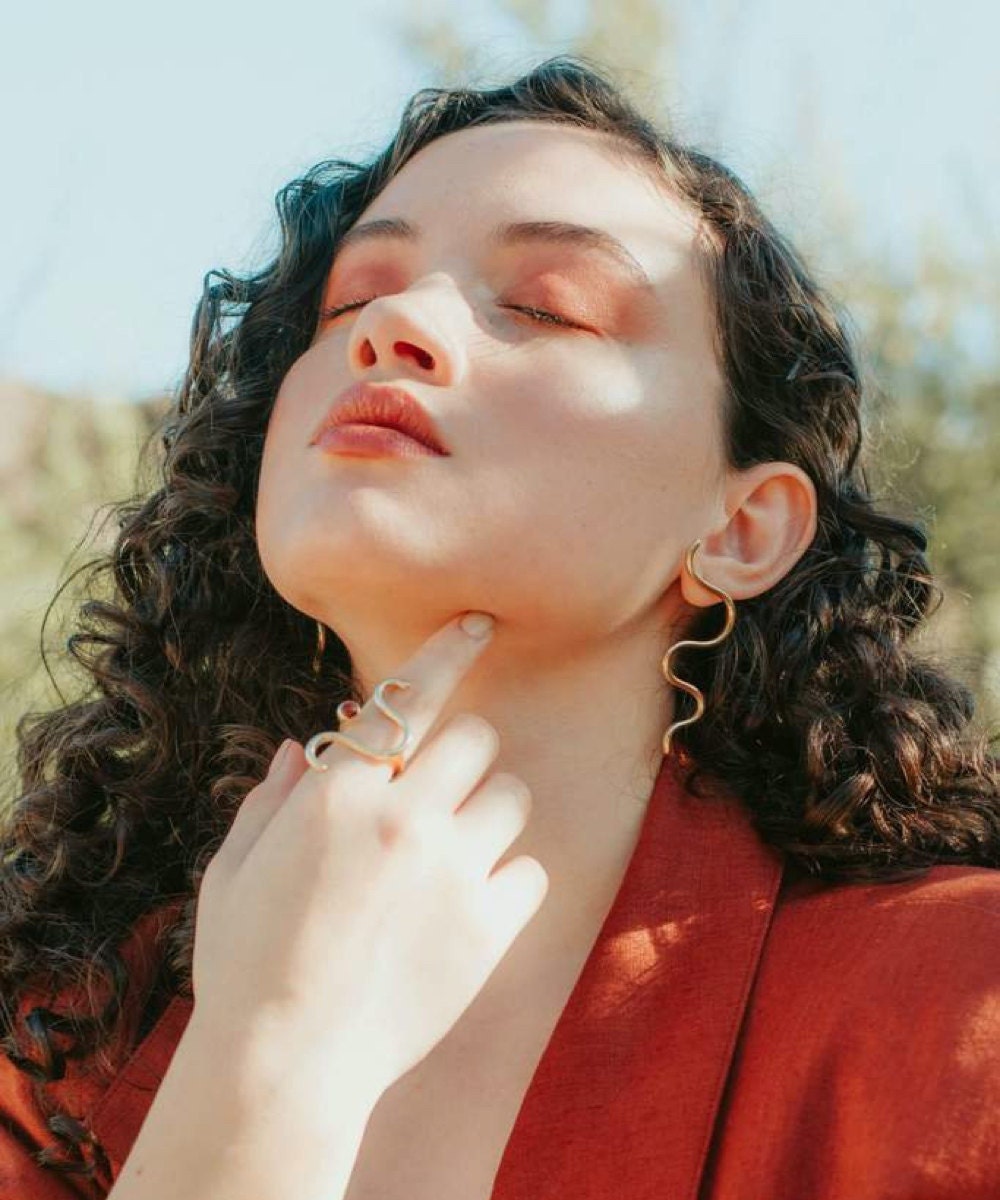 A model wearing a carnelian squiggle ring and matching earrings from Aleishla
