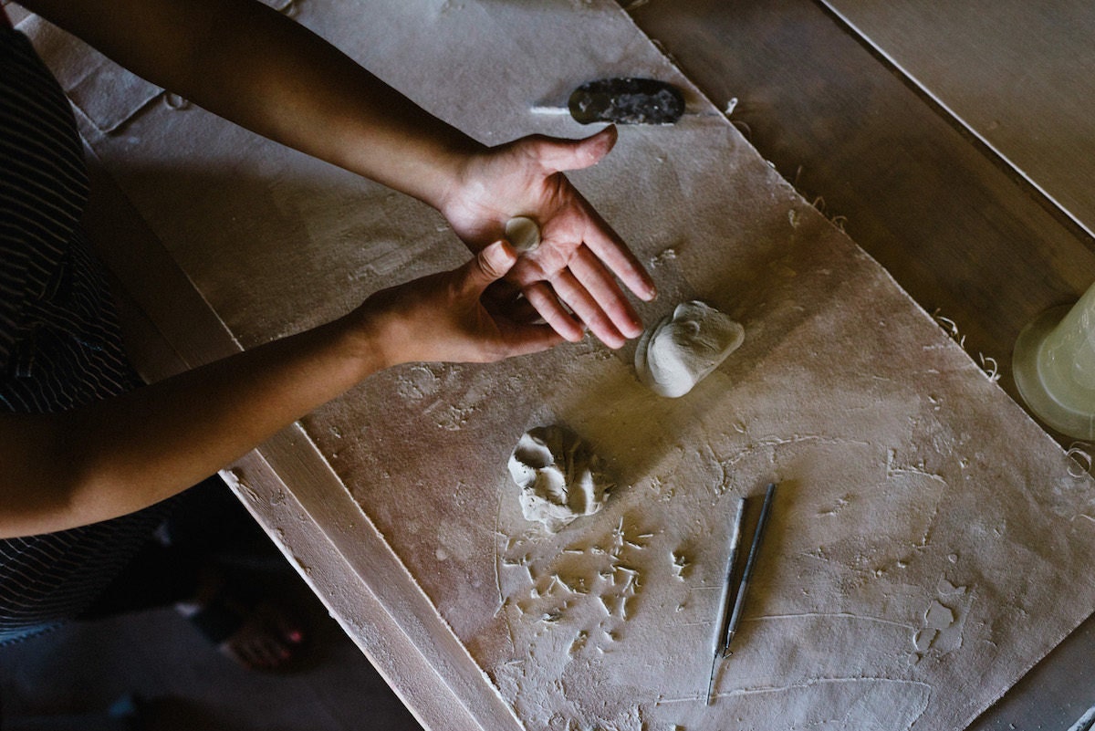 Yumiko forms a piece of clay to adorn one of her vessels