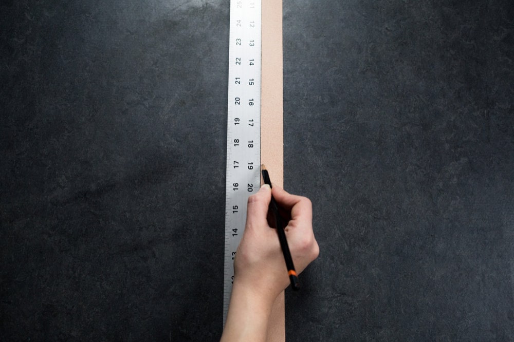 Measuring the leather straps alongside a ruler and marking off the correct length with a pencil