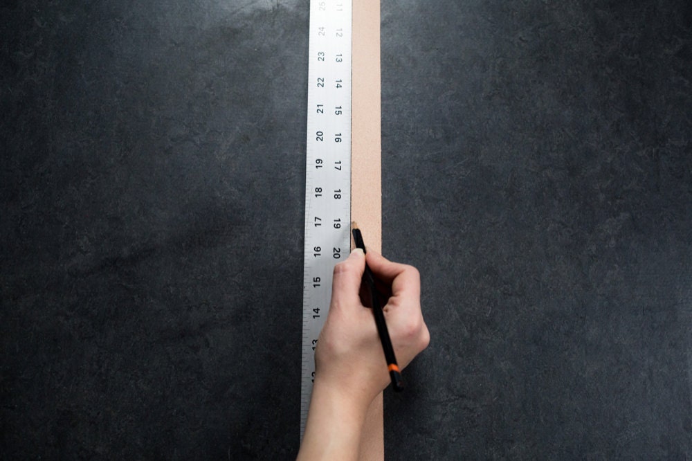 Measuring the leather straps alongside a ruler and marking off the correct length with a pencil