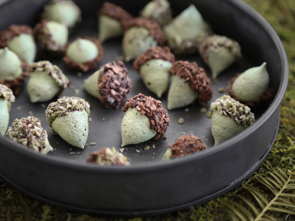 A baking pan full of cookies shaped like acorns.