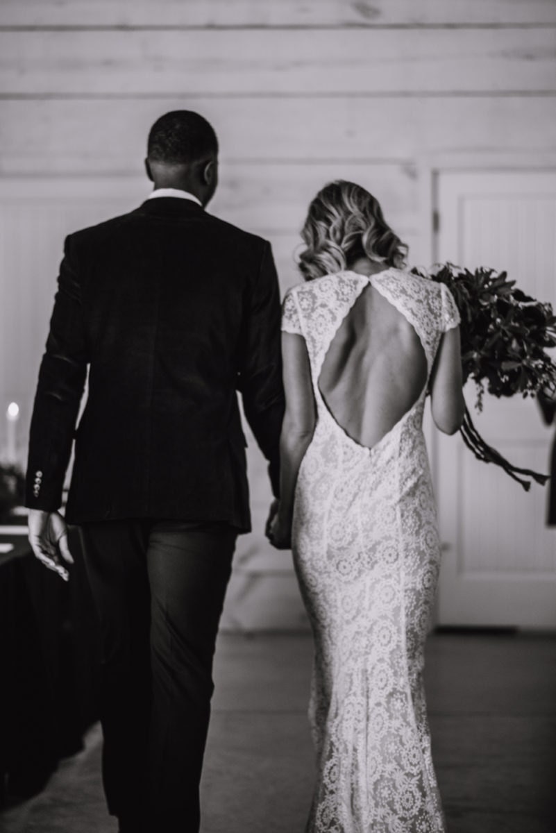 A black and white photo of Emily and Terrell from behind as they recess down the aisle