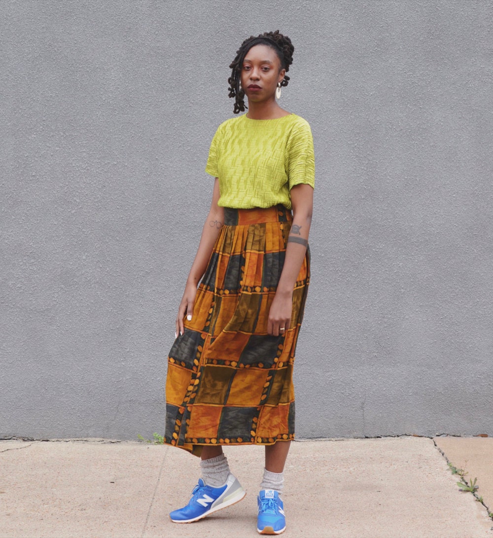 Rachelle models a lime green knit top and long, colorful skirt in earthy hues.