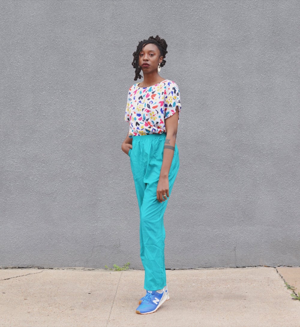 Rachelle models a colorful top nd bright blue pants.