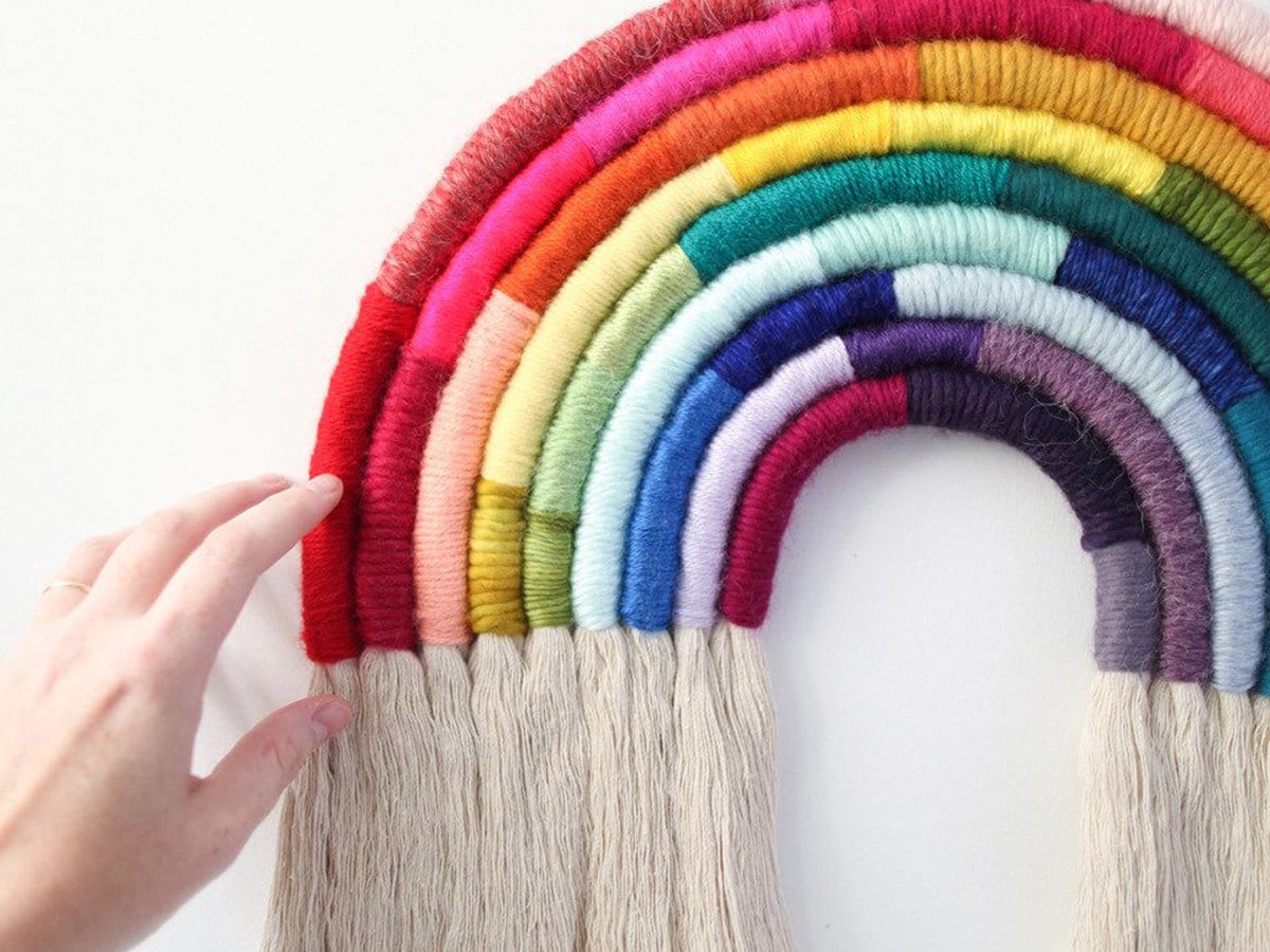 A model touches a fiber art rainbow.