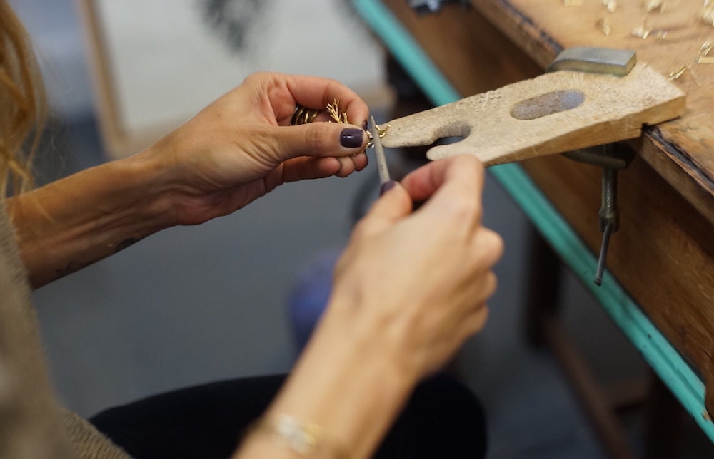 A closeup of Maria's hands as she works on her jewelry.