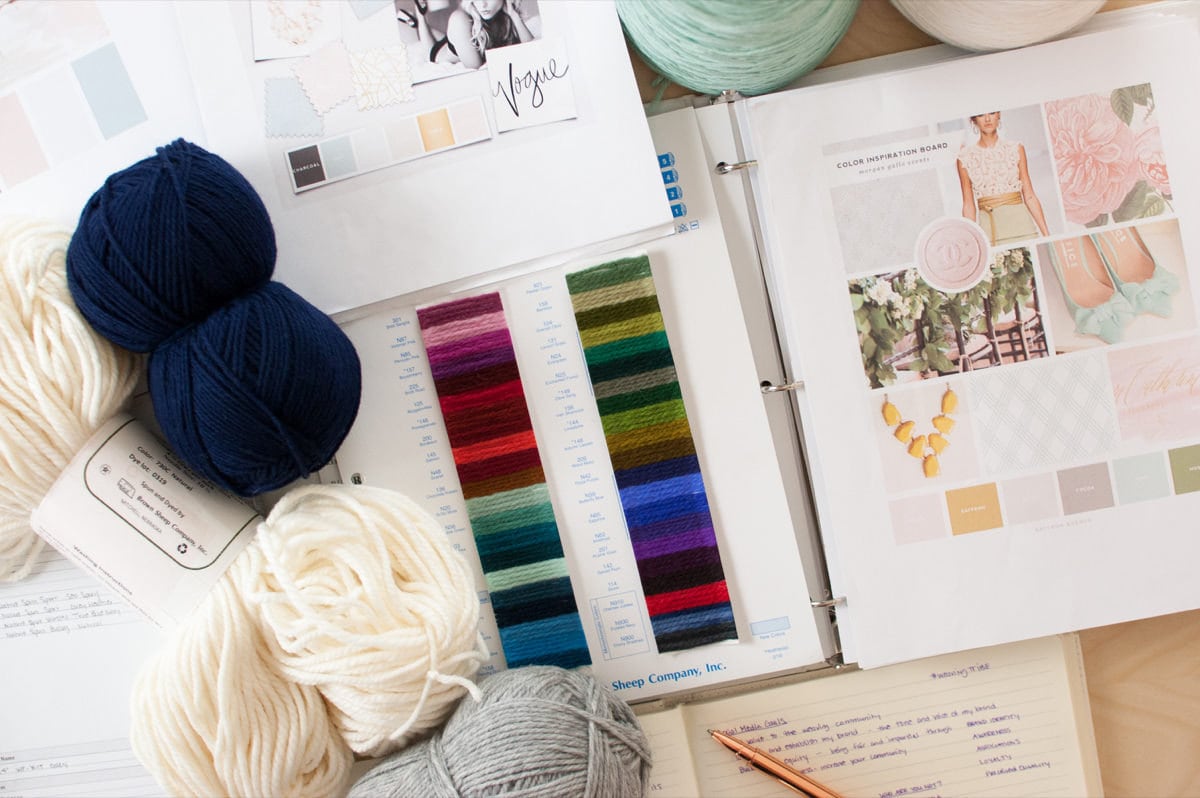A flat-lay of yarn and color swatches alongside mood boards crafted from magazines.